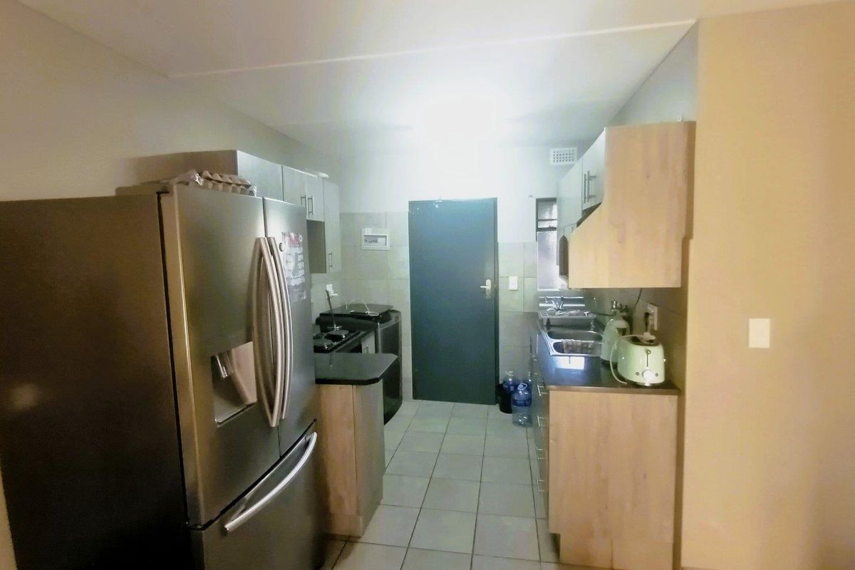 A functional kitchen featuring light wood-finish cabinetry, laminate countertops, tiled flooring, and a double sink, providing a practical workspace.