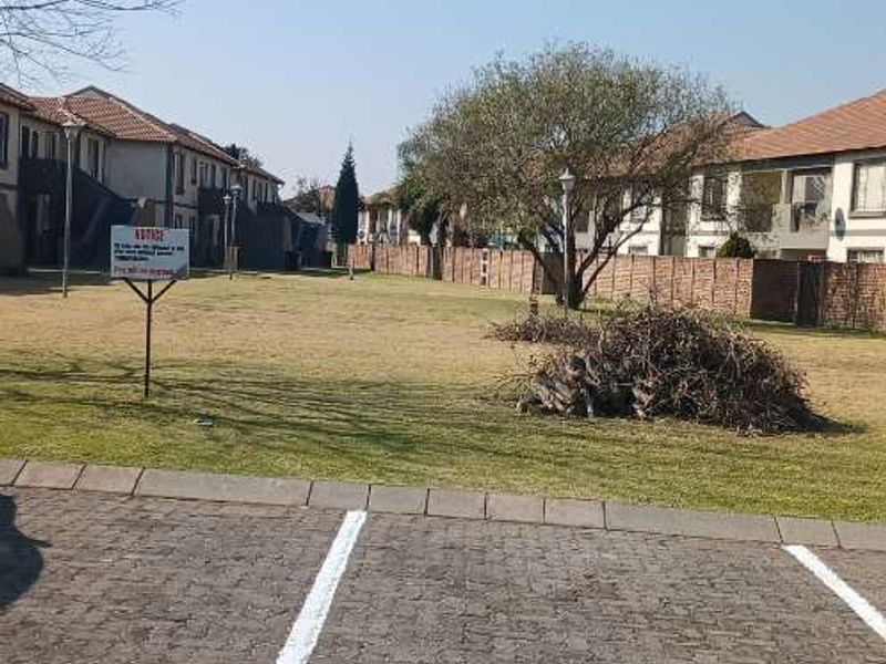 A view of the communal garden area and paved parking bays within the apartment complex grounds.