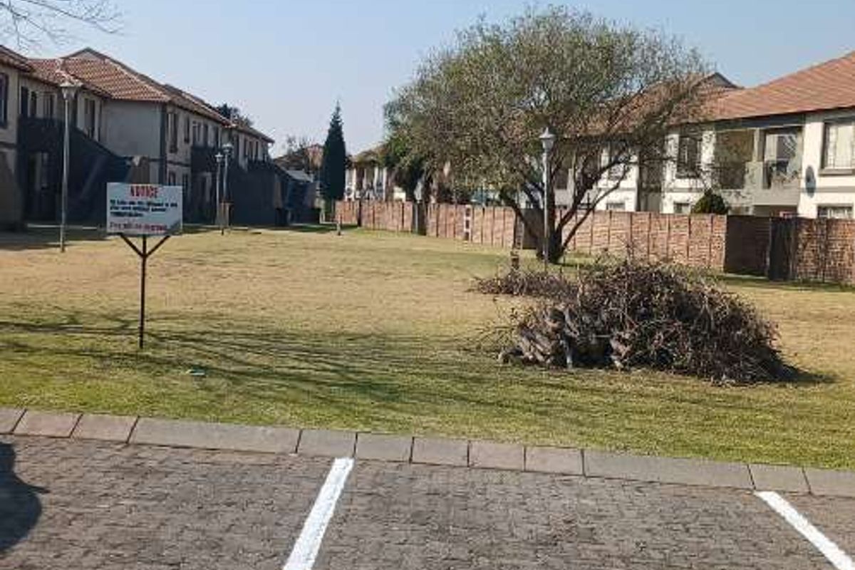 A view of the communal garden area and paved parking bays within the apartment complex grounds.