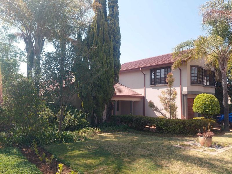 Front elevation of a two-story residential house featuring a tiled roof, bay windows, and a well-maintained landscaped garden.