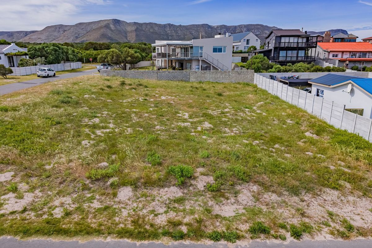 An elevated view of a vacant residential plot featuring natural vegetation and surrounding boundary walls in a developed coastal neighborhood.