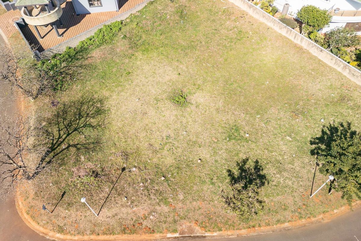 An aerial view of a vacant residential plot featuring established boundary walls and street-side access.