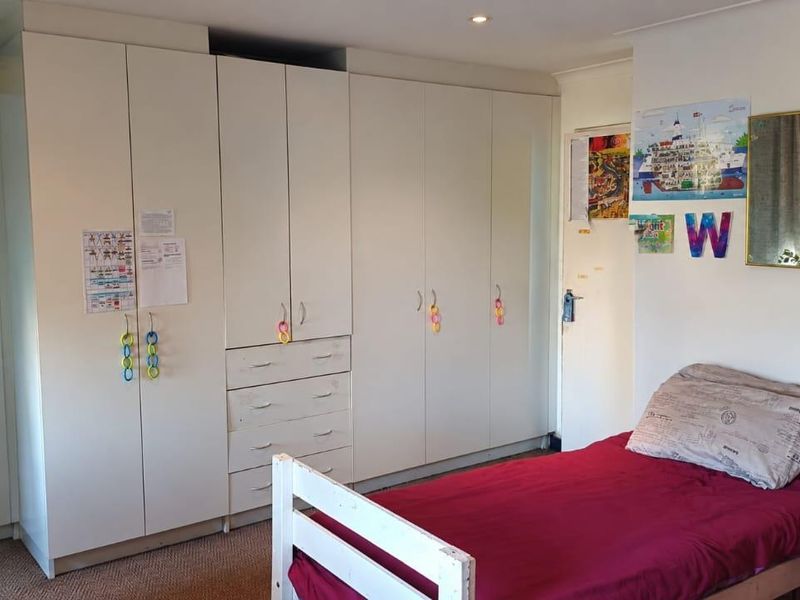 A bedroom featuring extensive white built-in cupboards providing ample storage space and recessed ceiling lighting.
