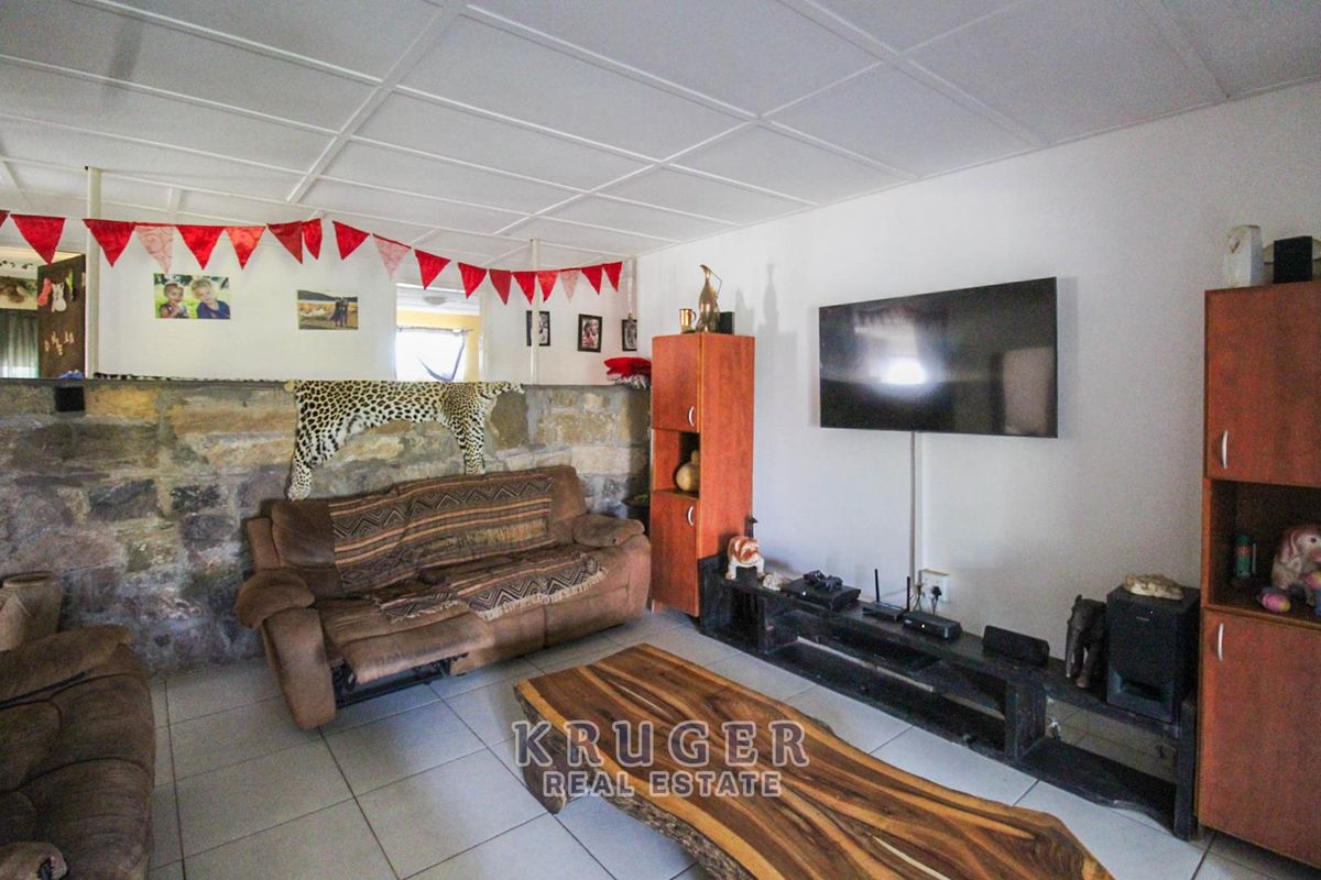 Living room featuring a rustic stone accent wall, tiled flooring, and a suspended ceiling, offering a casual and lived-in atmosphere.