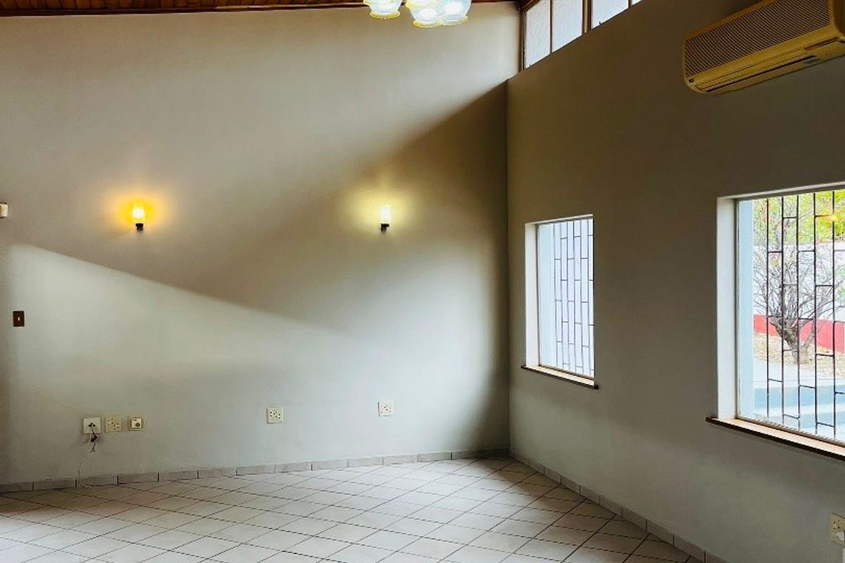 Spacious living area featuring a high timber-clad vaulted ceiling, ceramic tiled flooring, and wall-mounted air conditioning, offering a bright and open atmosphere.