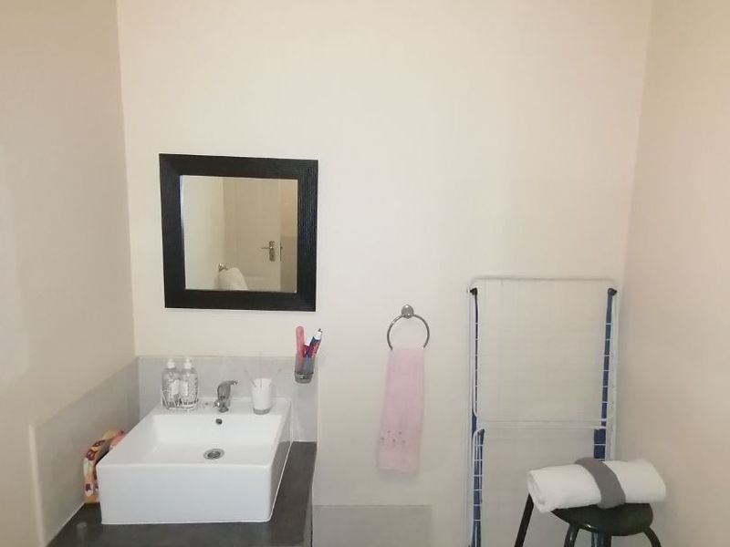 A compact bathroom featuring a modern vessel sink set on a dark vanity cabinet with a tiled splashback and wall-mounted mirror.