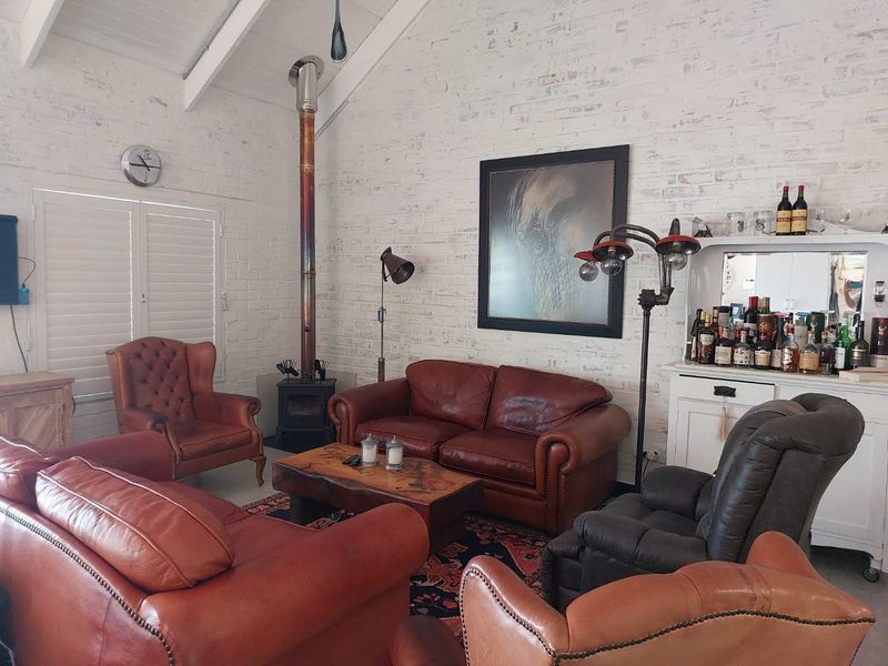 Spacious living room featuring a vaulted ceiling, white painted exposed brick walls, and a prominent wood-burning stove.