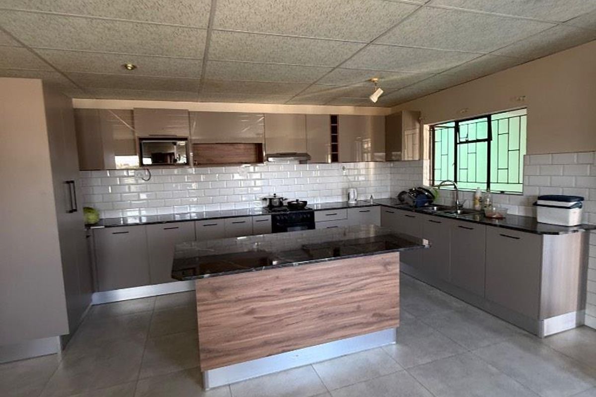 Modern kitchen featuring sleek cabinetry, a central island with stone countertops, subway tile backsplash, and tiled flooring throughout.