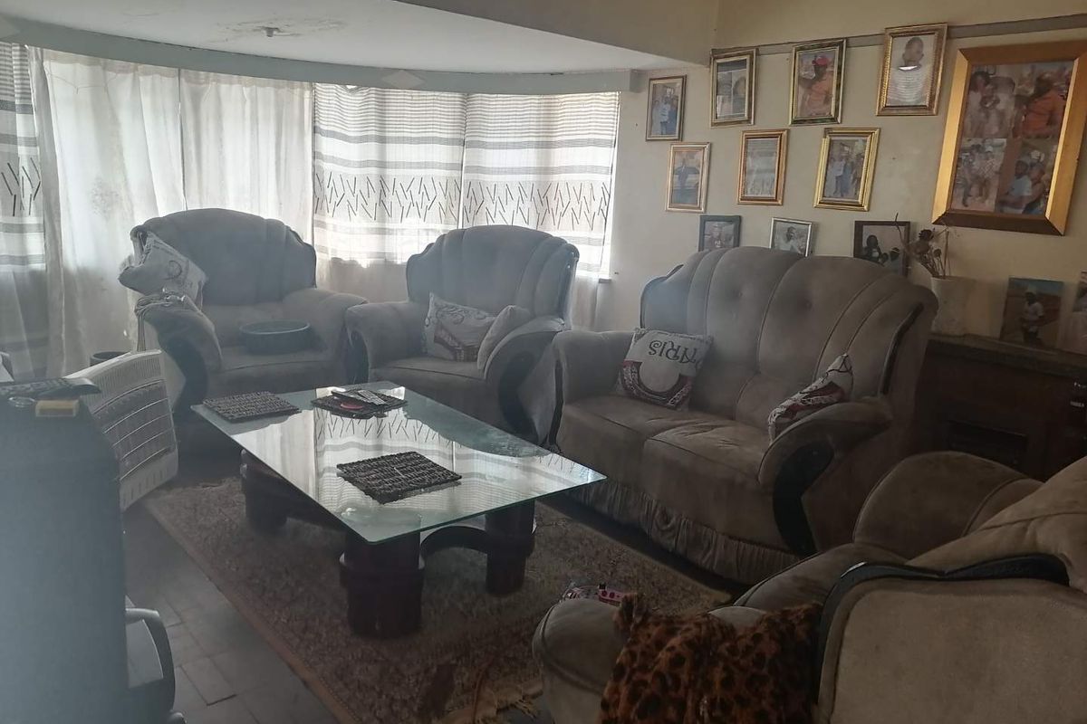 A living room area featuring a large window with curtains and visible signs of ceiling water damage requiring maintenance.
