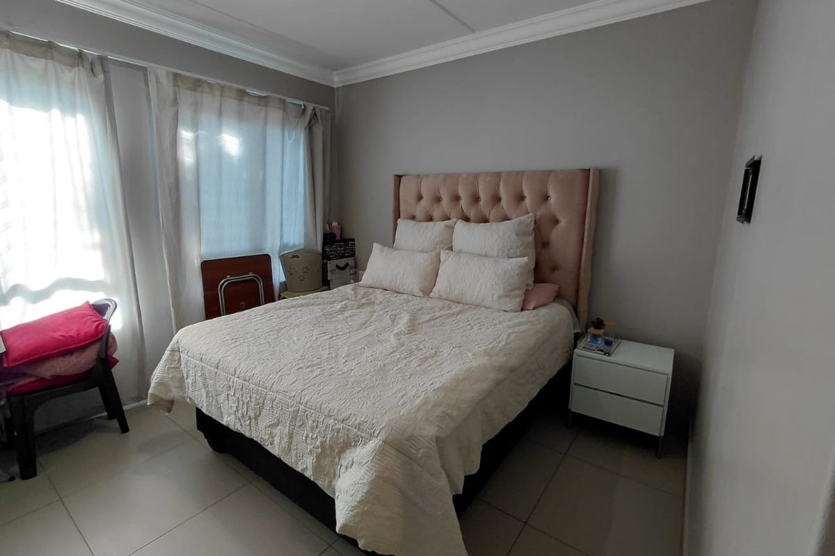 A well-maintained bedroom featuring neutral wall tones, tiled flooring, and decorative crown molding, providing a clean and functional living space.