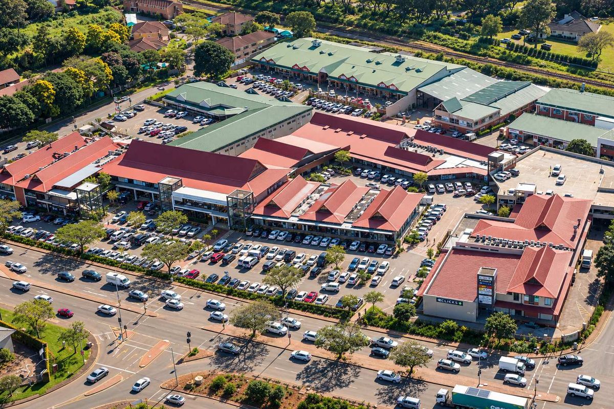 Aerial view of a large commercial office and retail complex featuring extensive parking facilities and multiple interconnected buildings with pitched metal roofing.