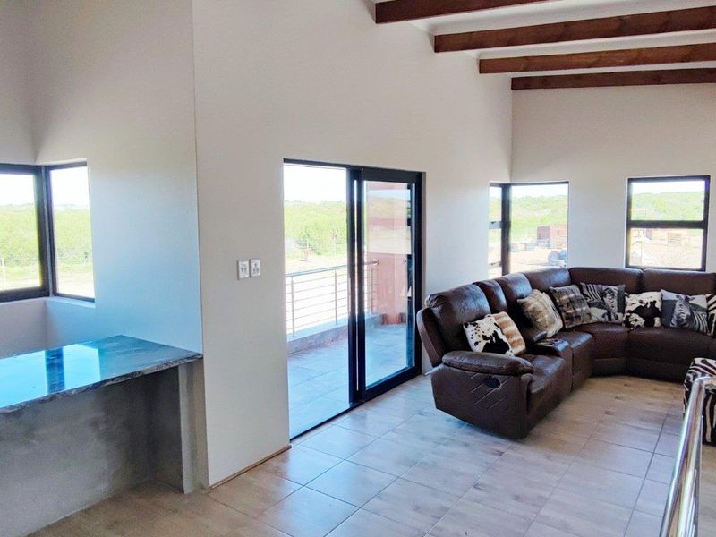 Spacious living area featuring exposed timber ceiling beams, tiled flooring, a built-in fireplace, and sliding glass doors leading to an outdoor patio.
