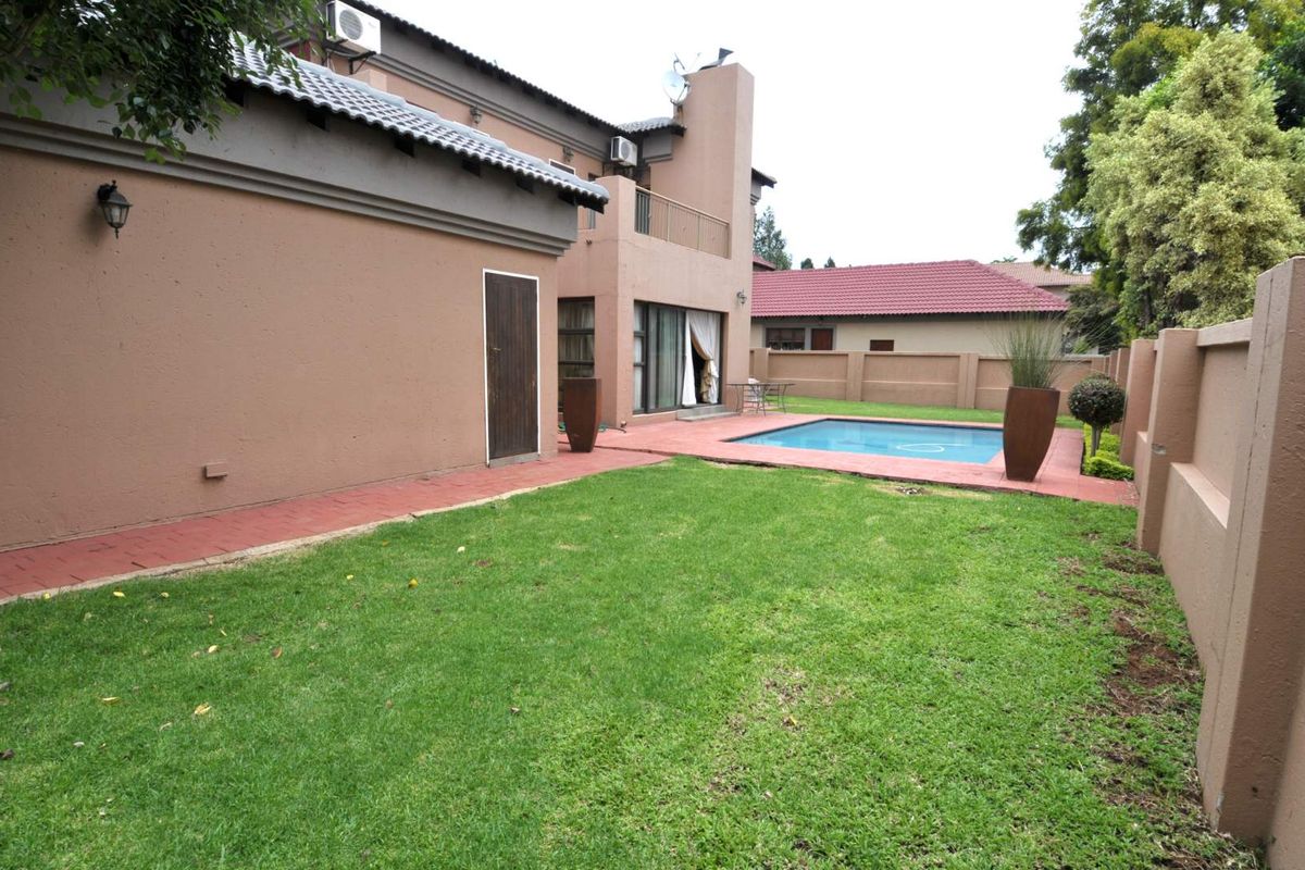 Rear garden featuring a swimming pool, paved patio area, and perimeter boundary walls, providing a private outdoor space for relaxation.