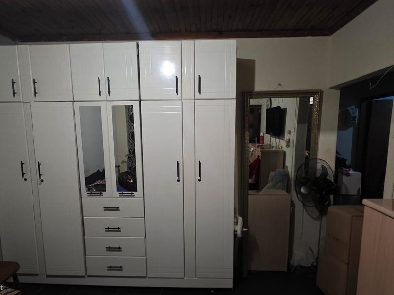 Bedroom featuring a large white built-in wardrobe with integrated drawers and a timber ceiling finish.
