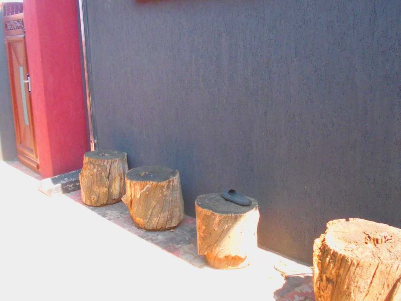 A close-up view of a textured exterior wall with red accents and a window frame.