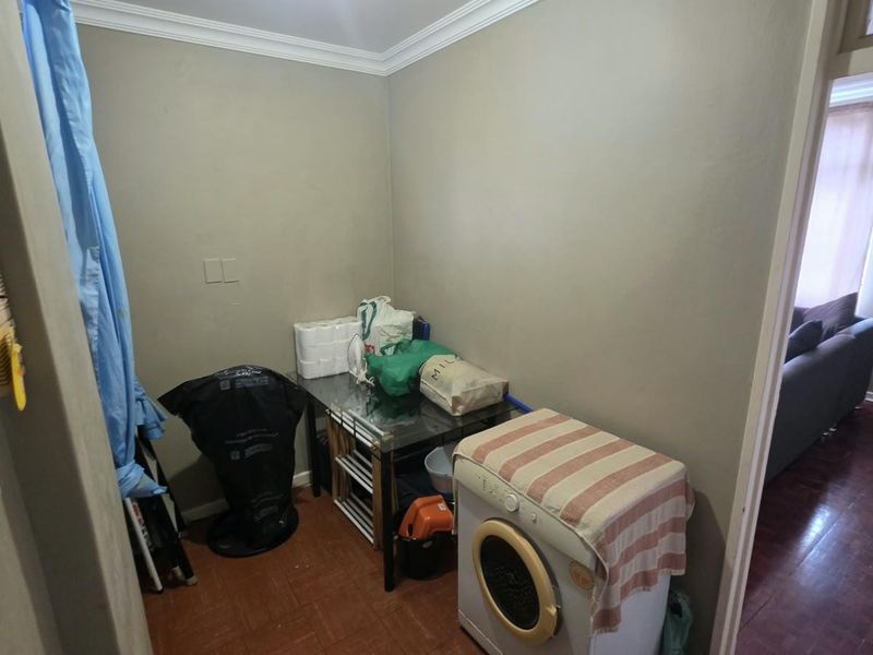 A functional laundry area featuring tiled flooring and coving, providing a dedicated space for utility tasks within the apartment.