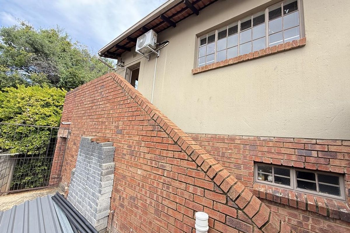 Exterior view of the property showing a brick staircase, external air conditioning unit, and multi-pane windows.