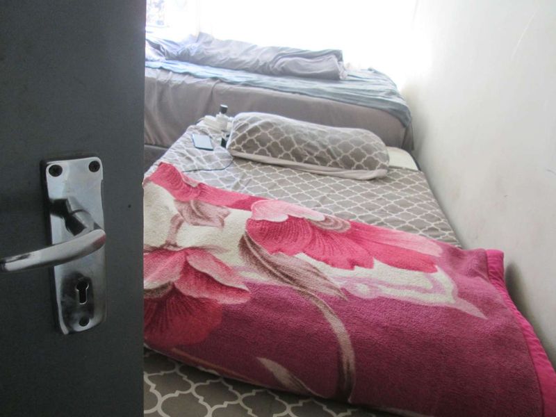 A view into a bedroom featuring a door handle in the foreground and beds arranged within the space.