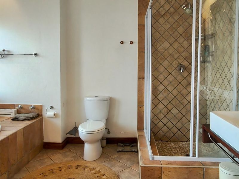 A functional bathroom featuring a built-in bathtub, separate shower enclosure, toilet, and a modern vessel sink with tiled finishes throughout.