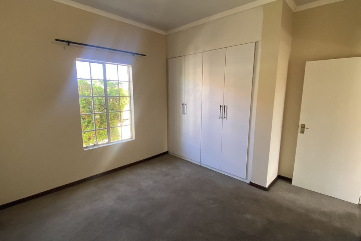 A clean, empty bedroom featuring neutral walls, carpeted flooring, and ample built-in cupboard storage space.
