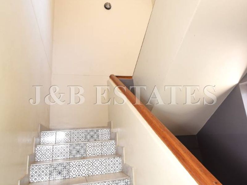 A staircase featuring decorative patterned tile risers and a wooden handrail, providing access between levels within the property.