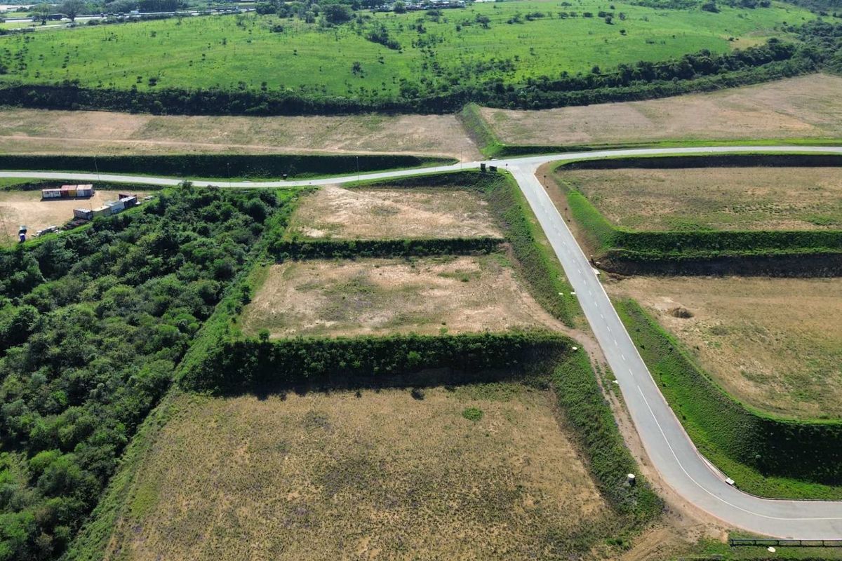 Aerial view of a vacant industrial land plot featuring terraced terrain, established retaining embankments, and direct access to a paved road network.