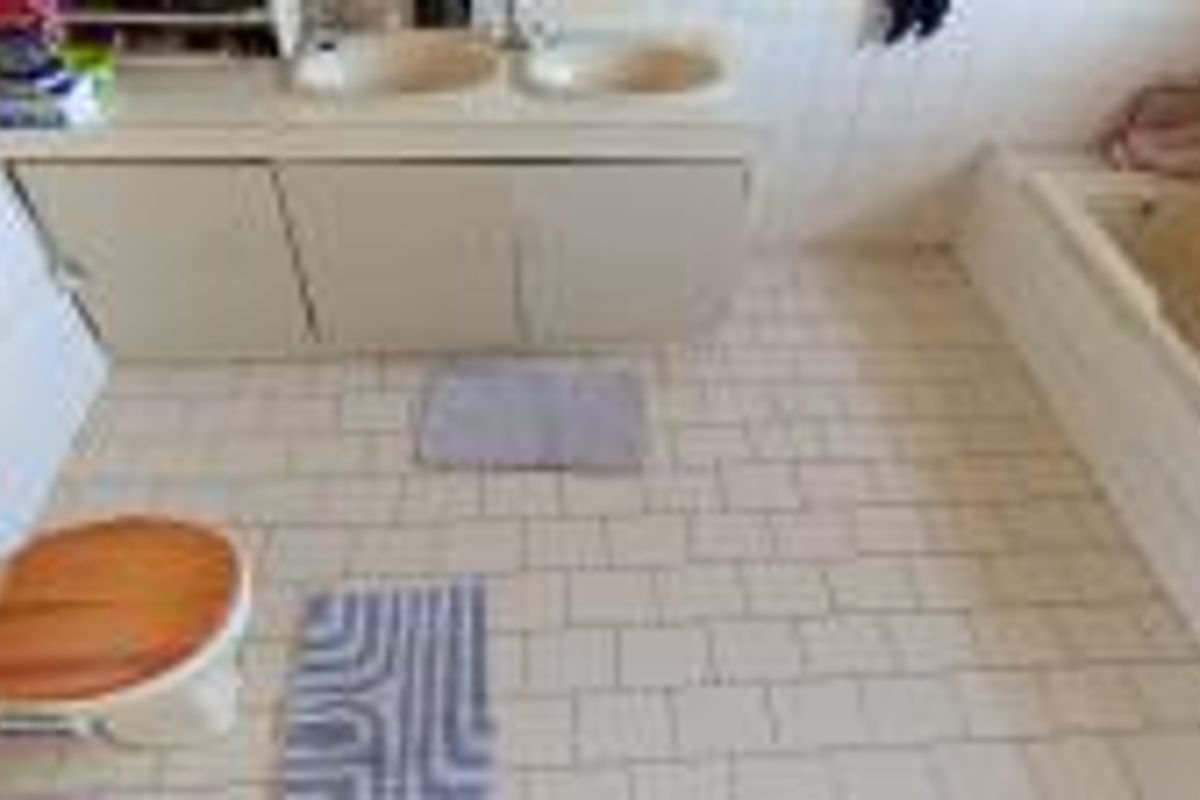 A dated bathroom featuring a double vanity, built-in bathtub, and tiled flooring, offering significant potential for a modern renovation.