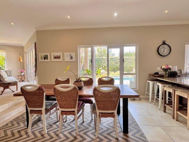 Spacious open-plan living and dining area featuring tiled floors, recessed lighting, and seamless access to the outdoor patio through large sliding glass doors.
