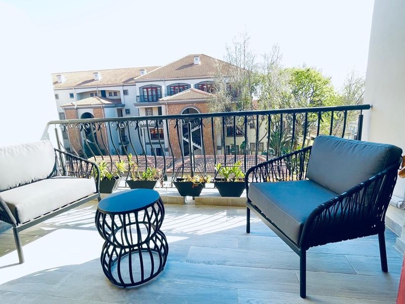 A well-maintained balcony featuring tiled flooring and a decorative wrought iron balustrade, offering an elevated view of the surrounding apartment complex.