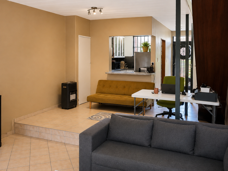 Open plan living area featuring tiled flooring, a pass-through kitchen window with a breakfast counter, and a staircase leading to the upper level.