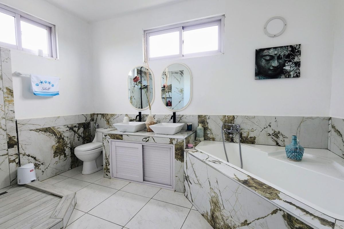 A modern bathroom featuring marble-look wall tiles, a double vanity with vessel sinks, a built-in bathtub, and a separate walk-in shower area.