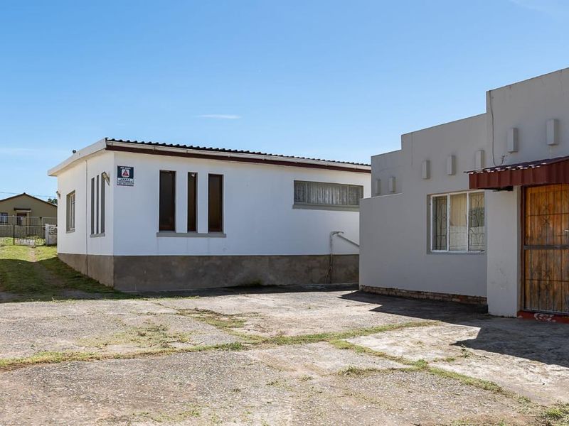 Exterior view of the property featuring a concrete driveway and building facade with security features.