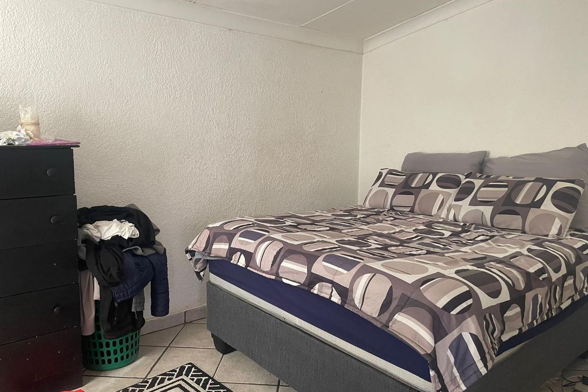 A functional bedroom featuring tiled flooring and a textured ceiling finish.