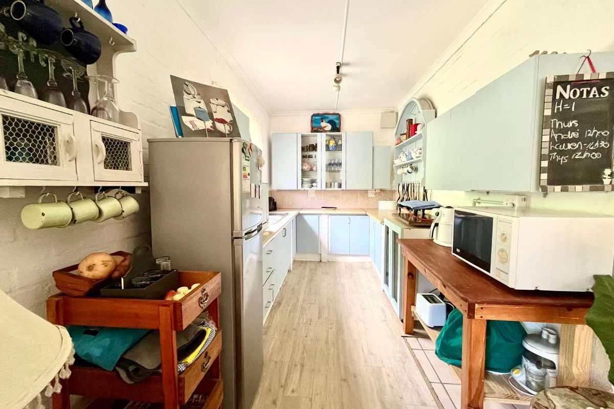 A functional galley-style kitchen featuring light blue cabinetry, laminate flooring, and a tiled backsplash, offering a practical layout for daily meal preparation.