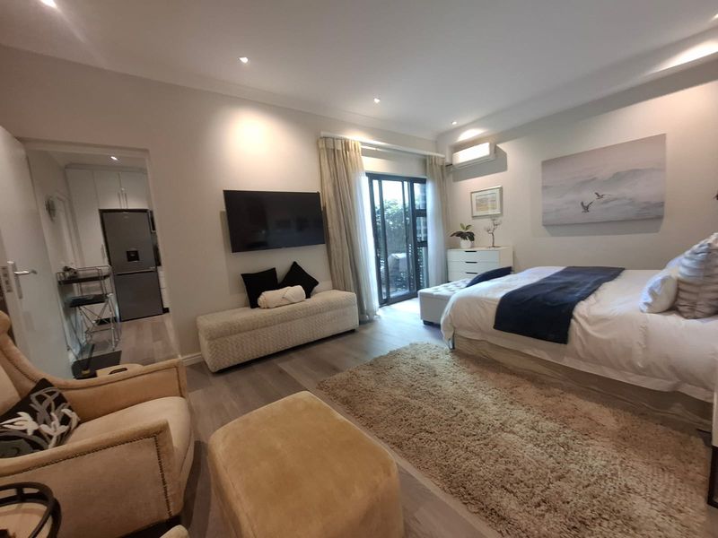 A well-maintained bedroom featuring laminate flooring, recessed lighting, a split-system air conditioner, and direct access to an outdoor area via sliding glass doors.