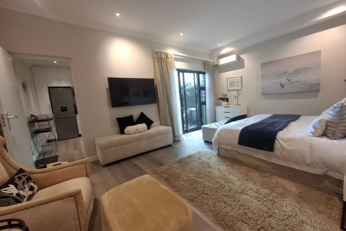 A well-maintained bedroom featuring laminate flooring, recessed lighting, a split-system air conditioner, and direct access to an outdoor area via sliding glass doors.