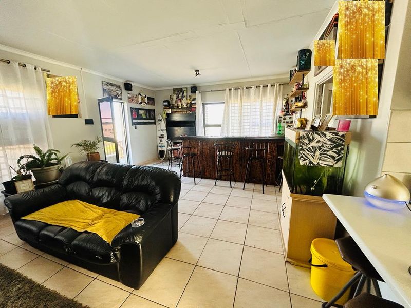 Open plan living area featuring a built-in bar, tiled flooring, and direct access to an outdoor space.
