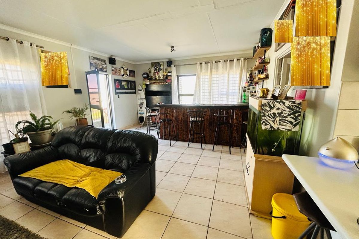 Open plan living area featuring a built-in bar, tiled flooring, and direct access to an outdoor space.