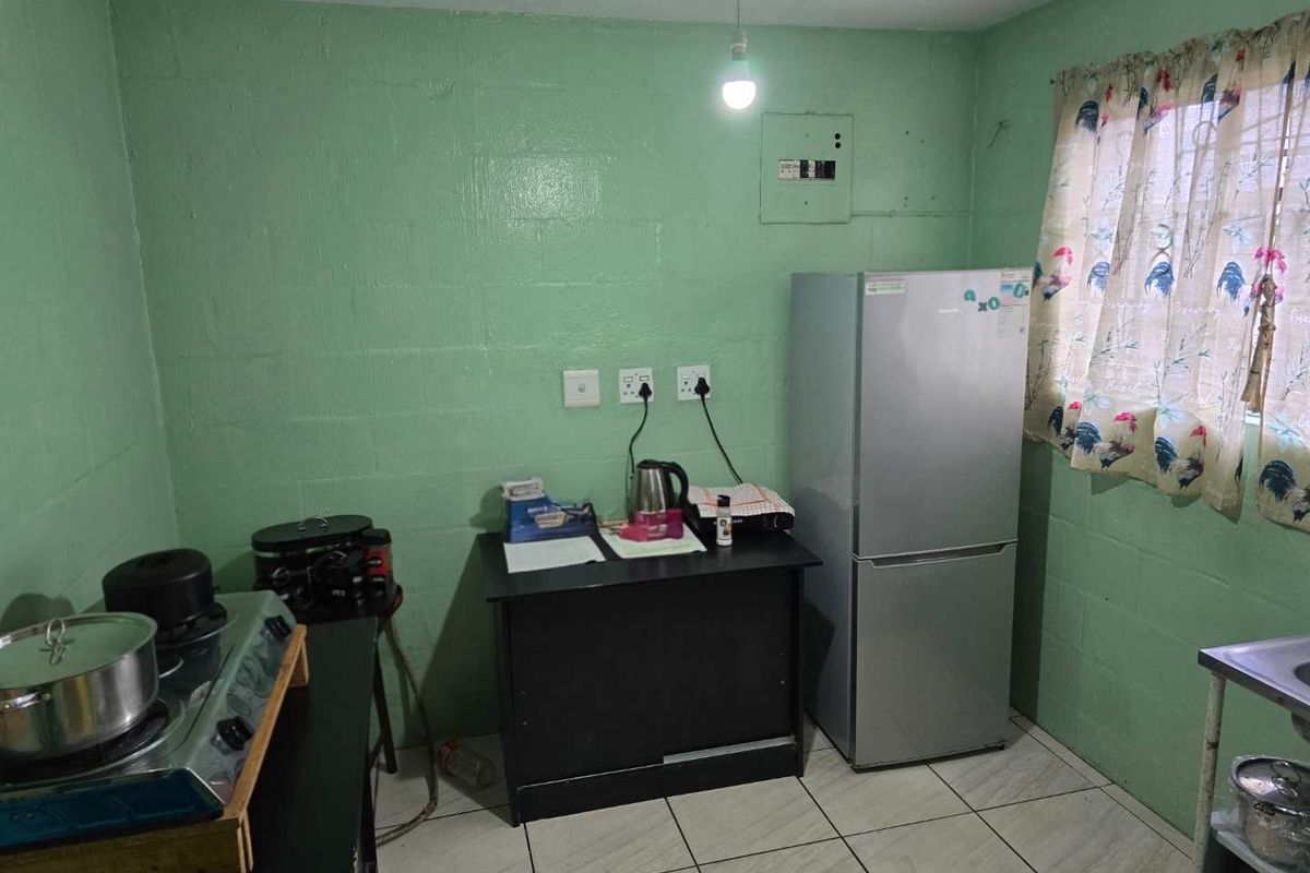 A basic kitchen area featuring tiled flooring and painted blockwork walls, requiring significant cosmetic updates and improved cabinetry to enhance functionality.