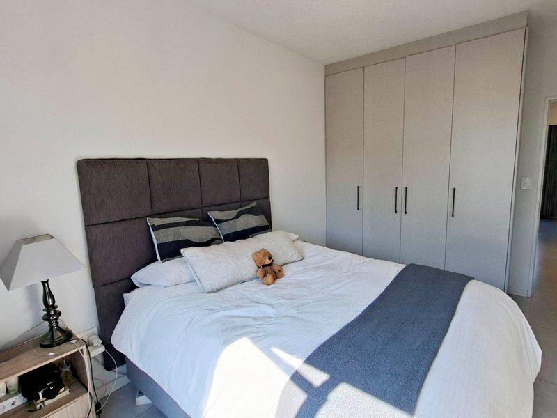 A well-maintained bedroom featuring neutral tiled flooring and ample built-in cupboard storage space.