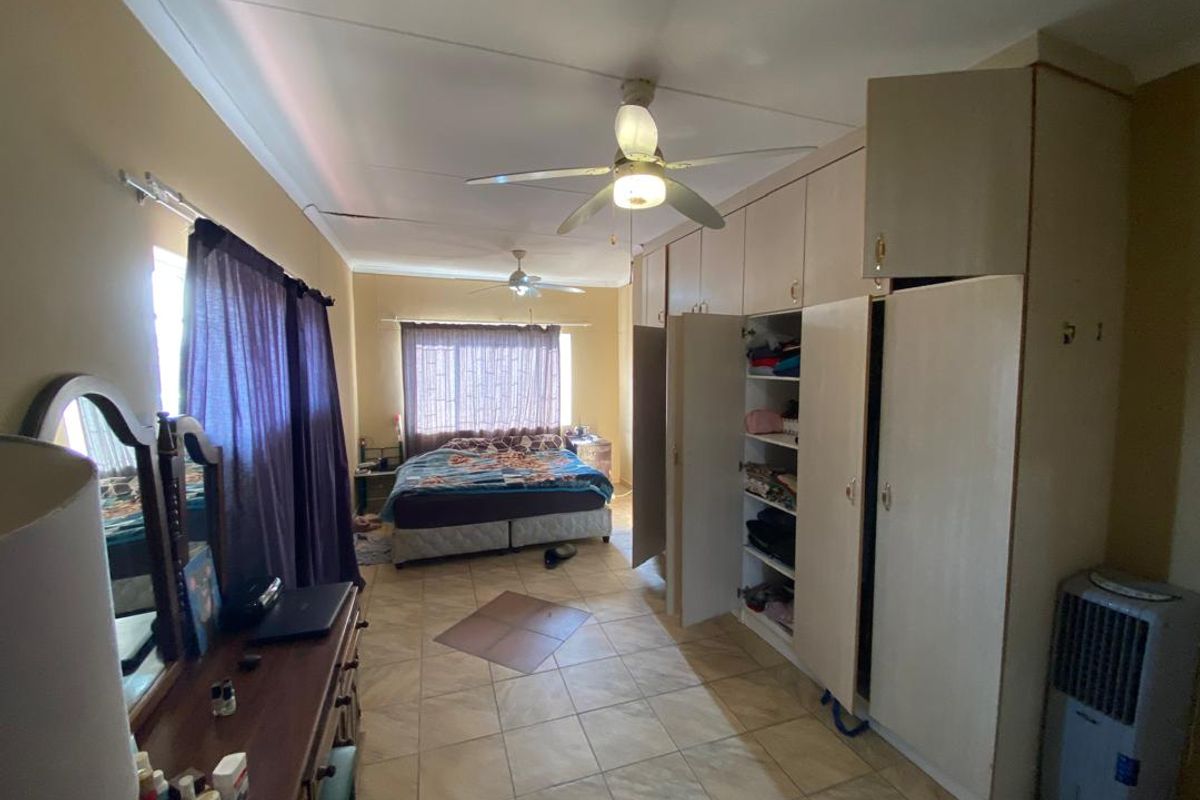 Spacious bedroom featuring extensive built-in cabinetry, tiled flooring, and dual ceiling fans.