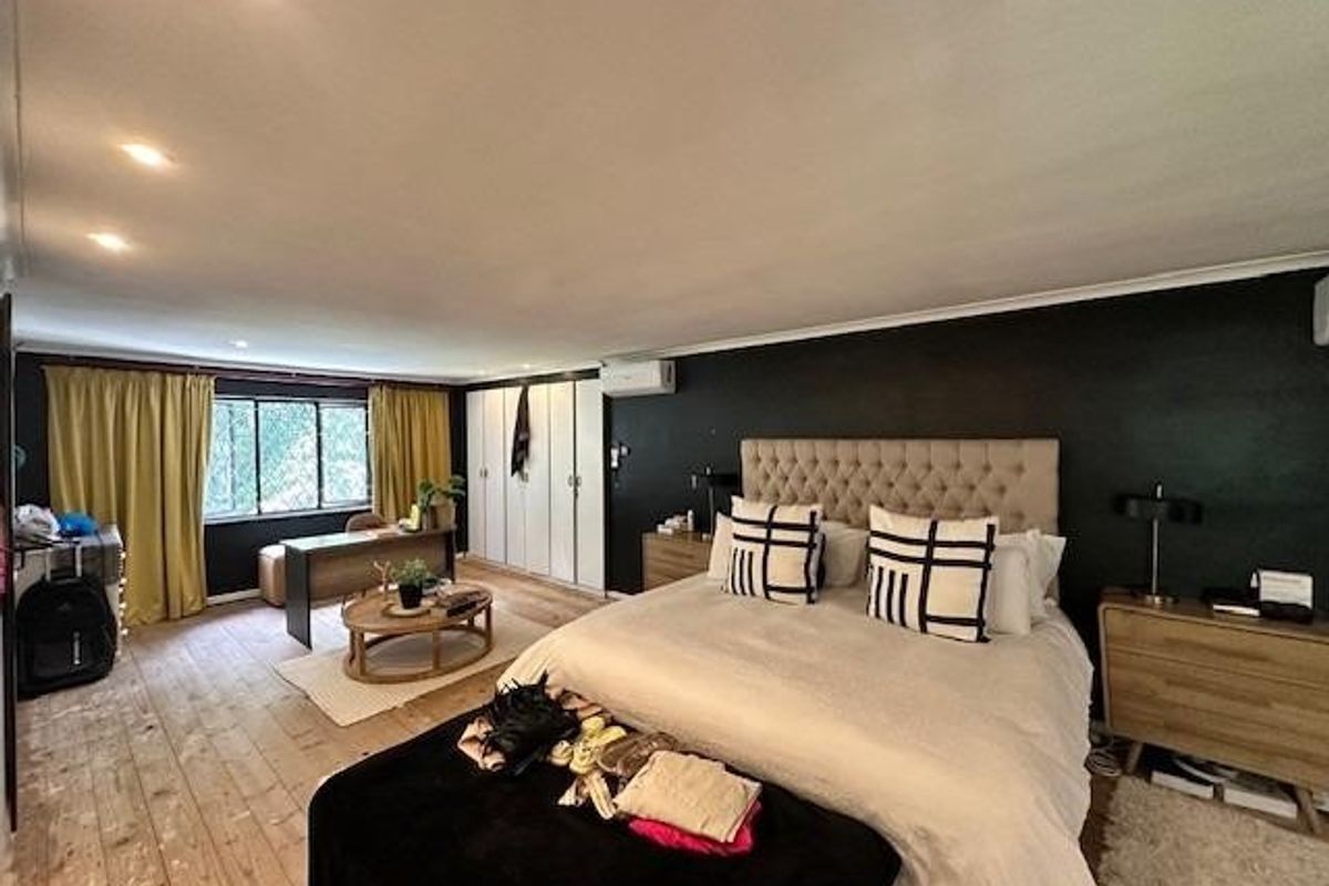 Spacious bedroom featuring timber flooring, built-in cupboards, recessed downlighting, and a wall-mounted split-system air conditioner.