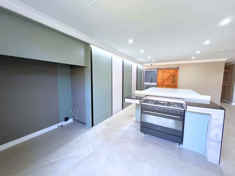 Modern kitchen featuring a central island with a gas stove, sleek built-in cabinetry, recessed lighting, and a rustic sliding barn door.