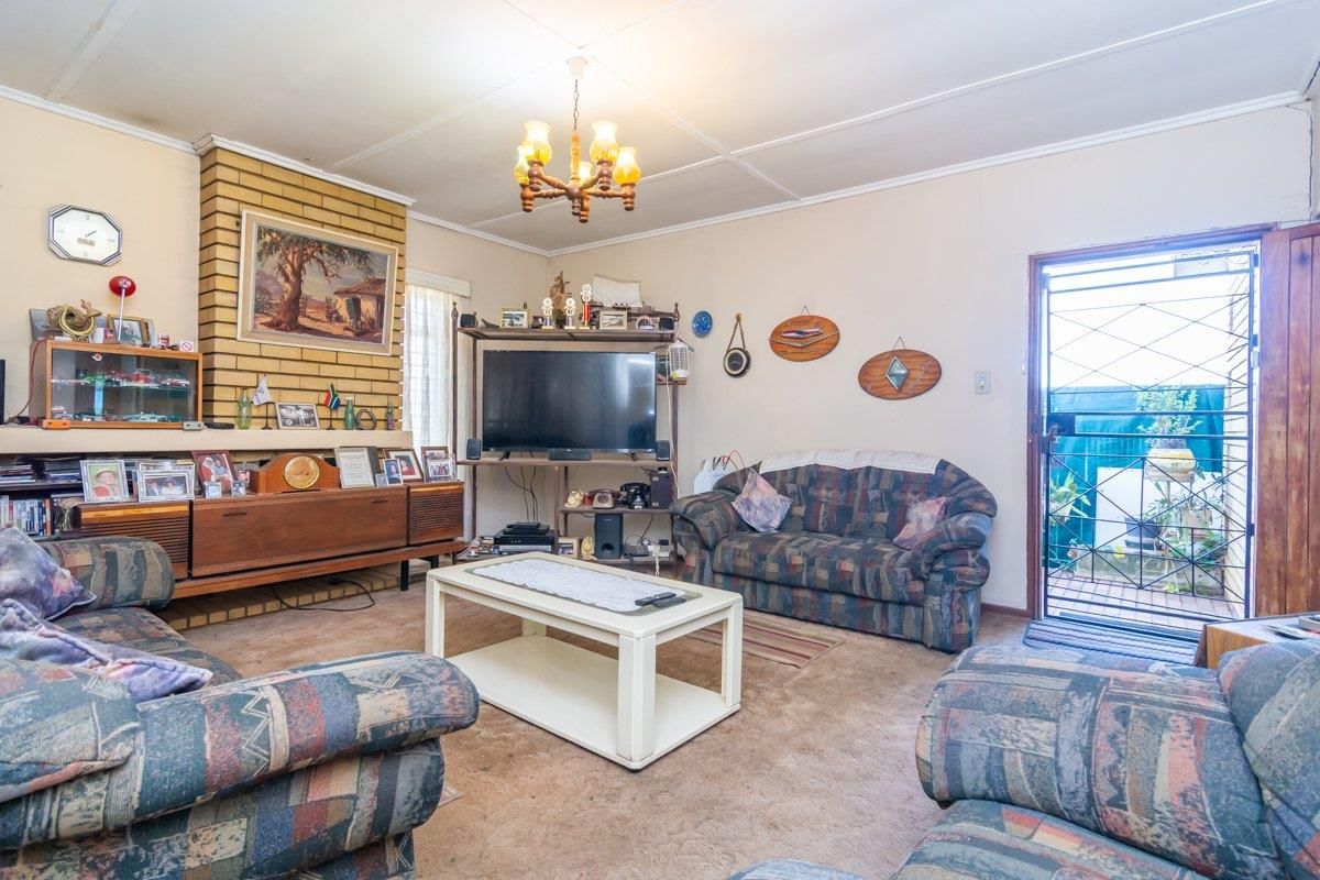 A living room featuring a brick fireplace, tiled ceiling, and direct access to an outdoor area through a security gate.
