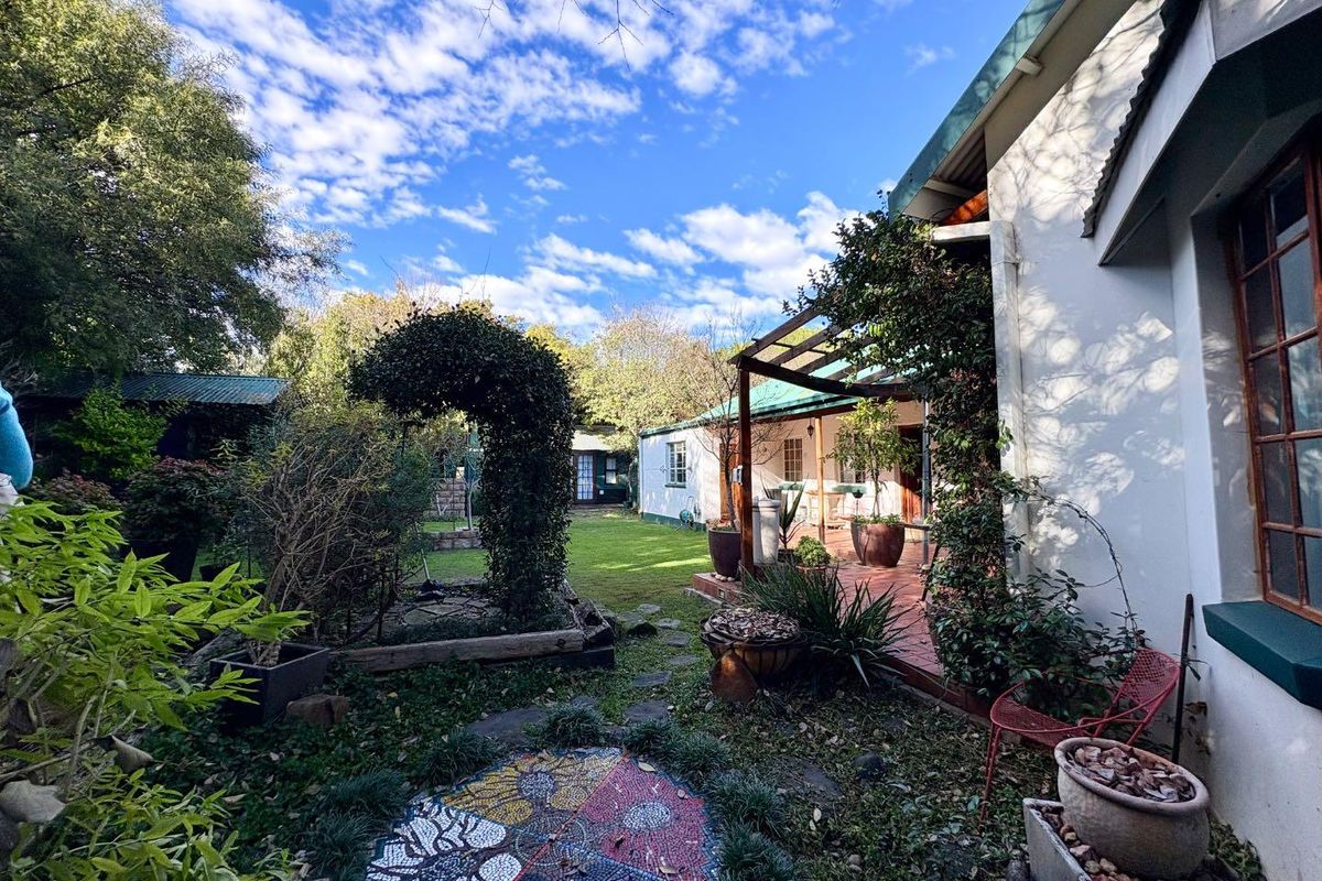A view of the rear garden featuring a covered patio area, established landscaping, and a mosaic feature, providing a tranquil outdoor living space.