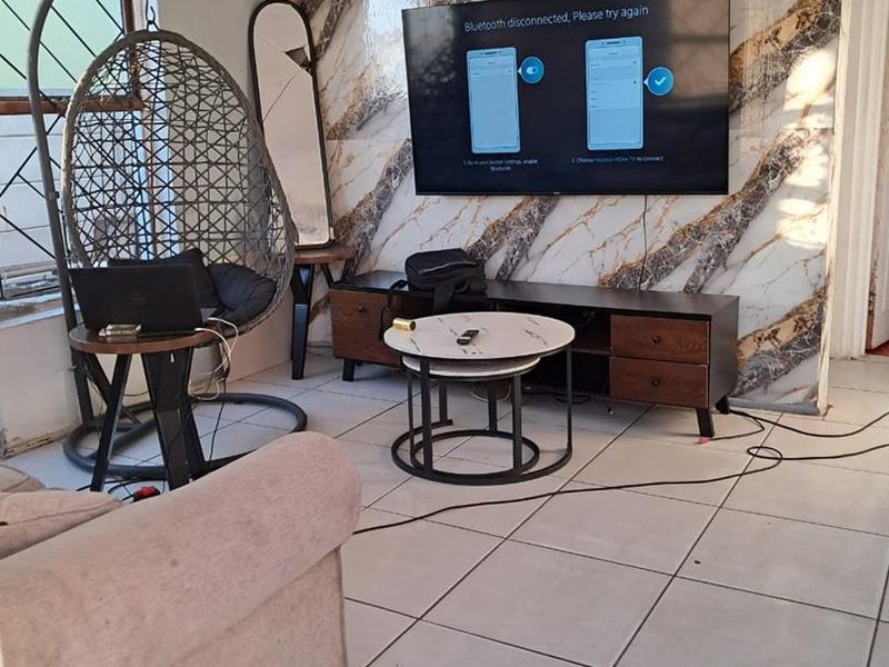 Living room featuring tiled flooring and a decorative marble-effect feature wall, currently requiring minor finishing touches to wall edges and cable management.