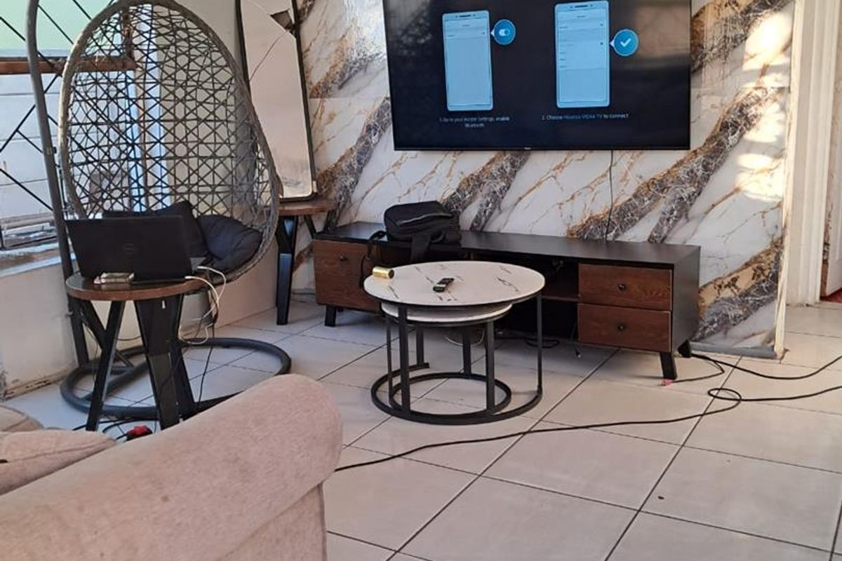 Living room featuring tiled flooring and a decorative marble-effect feature wall, currently requiring minor finishing touches to wall edges and cable management.