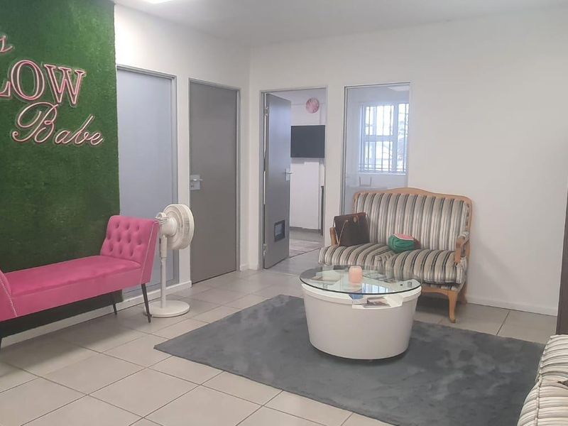 A functional reception or waiting area featuring tiled flooring, neutral walls, and access to multiple internal rooms.
