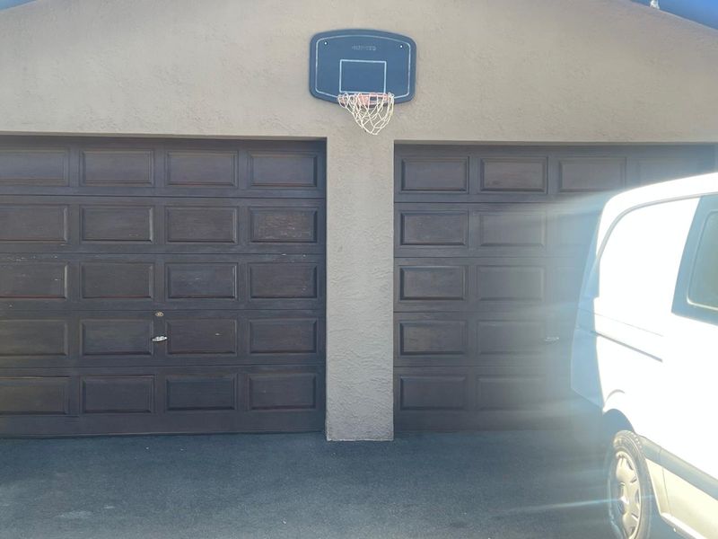 A double garage featuring dark-toned panelled doors and a stucco exterior finish.
