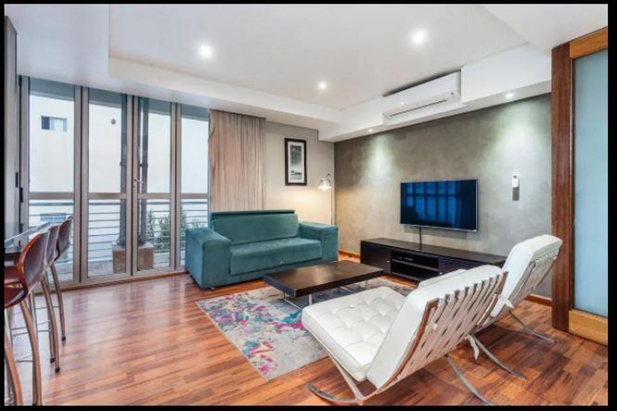 A well-maintained living room featuring hardwood flooring, recessed lighting, a split-system air conditioner, and large sliding glass doors leading to a balcony.